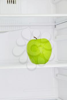 Lifestile concept.Big green apple in domestic refrigerator taken closeup.Toned image.