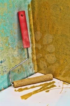 Roller paintbrush near grunge yellow painted wall.Toned image.