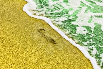 Human trace on sandy beach near turquoise sea surf taken closeup.Toned image.