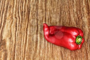 Single Red sweet pepper on grunge wooden background taken closeup.Toned image.