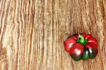 Red sweet pepper on grunge wooden background taken closeup.Toned image.