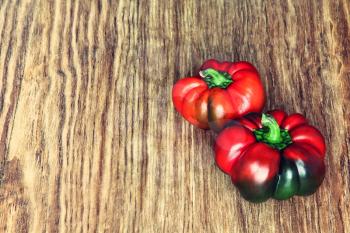 Two sweet red peppers on rustic wooden background taken closeup.Toned image.