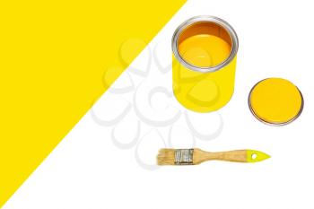 Bank of yellow paint and paintbrush on white background with empty space for text.