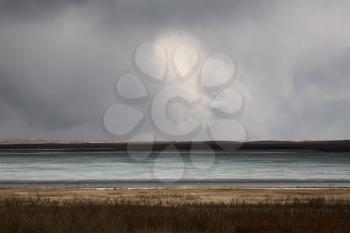 Storm clouds over frozen slough in early spring