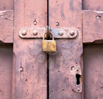 abstract  padlock rusty brass brown knocker in a   closed wood door crenna gallarate varese italy