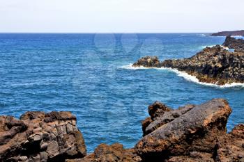 brown rock in white coast lanzarote   spain   beach  stone water  and summer hervideros