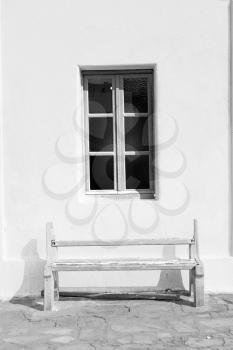 chair and stone pavement in the greece island of paros old bench near a brick antique church  wall 