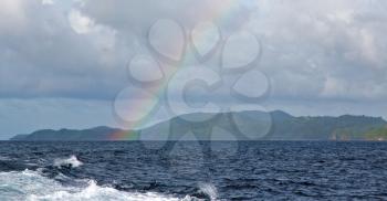 from a boat the rainbow from  ocean and island in background