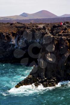 people   coastline stone volcanic spain  water  in lanzarote los hervideros sky cloud beach  and summer 
