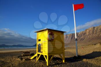 red flag water lifeguard chair cabin in spain  lanzarote  rock stone sky cloud beach  musk pond  coastline and summer 
