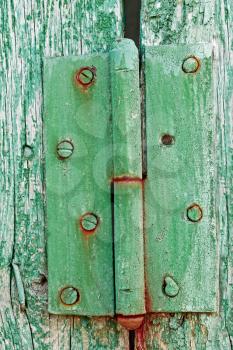 Old metal rusty hinges on the wooden boards covered with multilayered shelled with green and turquoise paint