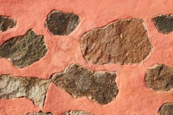 Granite stone boulders interspersed in concrete painted in reddish color