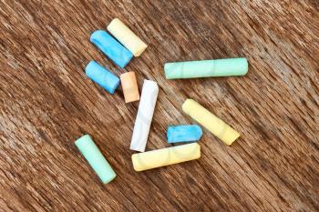Several cylindrical pieces of colorful chalk on the old eroded brown board