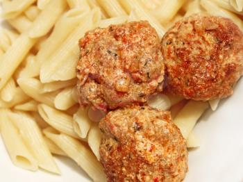 Three meatballs with sauce over plain cooked pasta close up 