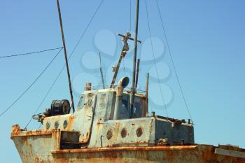Old rusty small ship against a cloudless sky
