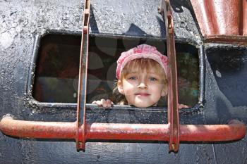 Beautiful joyful little girl in cap was inside a welded metal structure of attractions for children