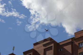 Silhouette of plane above building against the blue sky 18543