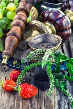 details vintage smoking hookah on wooden table on background of ripe grapes and strawberries