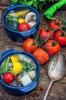 traditional soup of fresh vegetables in blue pot on wooden background.Photo tinted