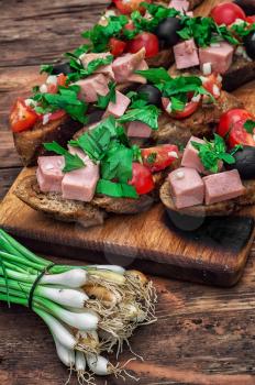 sandwiches with meat ,fresh tomatoes, onions and olives on wooden table top.Photo tinted