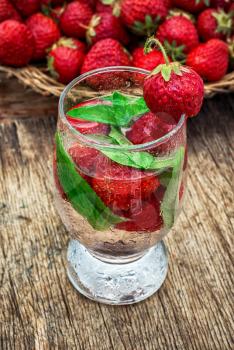 glass with drink of strawberries and mint on the background of the basket full berries.Selective focus.Photo tinted