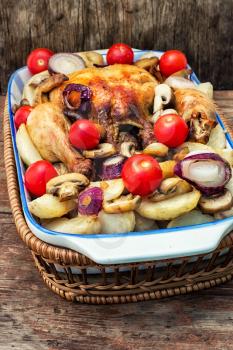 young chicken baked with potatoes,mushrooms and vegetables in the baking dish.Photo tinted.Selective focus