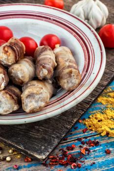 Turkey sausages roasted on round plate on wooden surface with tomatoes and spices.