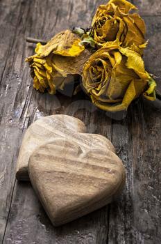 hand-carved symbolic wooden heart on a background of yellow roses