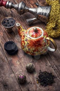 accessories to Smoking hookah and dry tea leaves.image is tinted in vintage style
