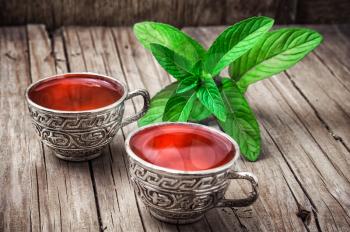two iron bowls with herbal tea on background of mint leaves