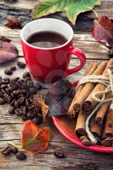 Stylish porcelain Cup of coffee on  background decorated with spices and strewn with autumn leaves