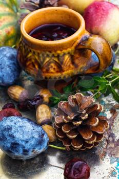 Stylish cup of autumn tea infused with herbs on the background of the fruit