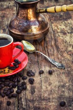 Red coffee Cup and saucer on the background of spilling the beans and cezve