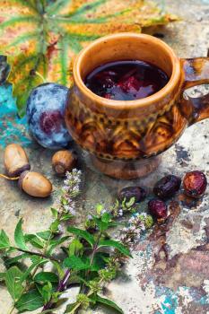 Mug with herbal medicinal tea on an autumn fruit,chestnuts and acorns on metal background.