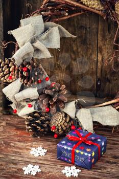 gift box on the background of a wicker wreath decorated for Christmas with pine cones and berries