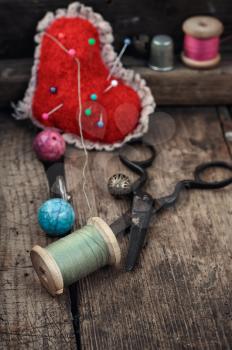 Old scissors,spools of thread,buttons and beads on wooden table