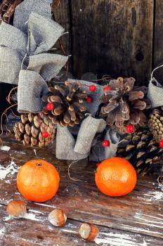 Woven Christmas wreath decorated with cones on background of ripe tangerines