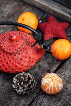 Red cast iron teapot,tangerine,bump and toy on wooden background