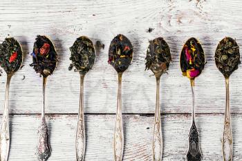 Seven kinds of tea infuser in tea spoons on wooden background