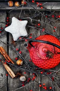 Red metal kettle,branches with berries on wooden background