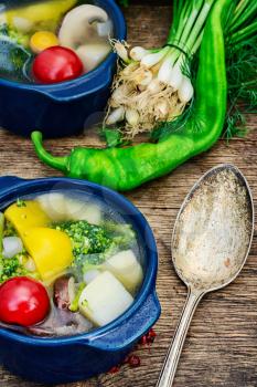 vegetable soup with peppers,potatoes,mushrooms and cauliflower on wooden background