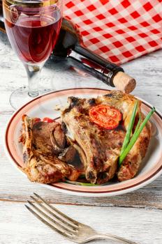 Portion of baked beef on the bone and a glass of red wine