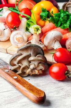 Fresh mushrooms,tomatoes,peppers and onions on a light wooden background