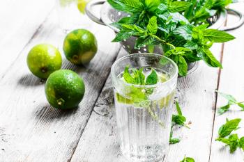 Glass cup with drink of water with lime in light background