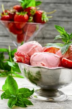 Ice cream with strawberries and leaves of mint in the iron bowl