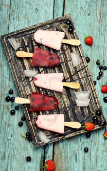 Berry ice cream on stick posted on stylish cutting board with berries and ice