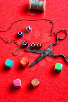 beads for needlework and scissors on bright red background