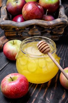 jar of honey and wooden basket of apples