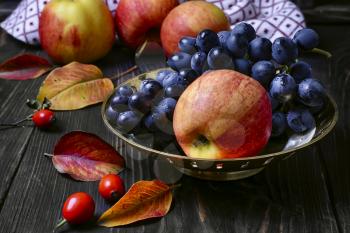 Autumn harvest of apples and grapes on a dark background