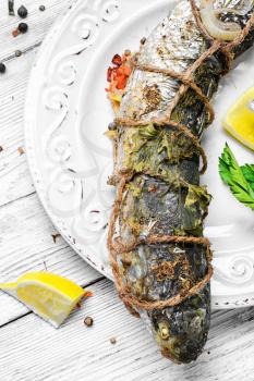 whole carcass of fish grilled on light plate on light background